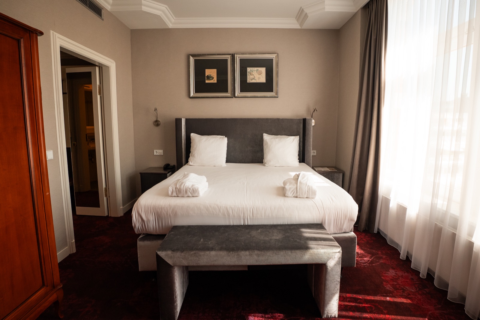Classic Kurhaus hotel room with velvet headboard and sunlight through sheer curtains